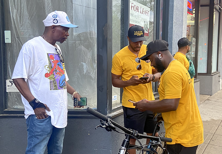 Brothers Jarone, center, and Jaquawn, center right, help a resident who asked about resources to look for housing.
