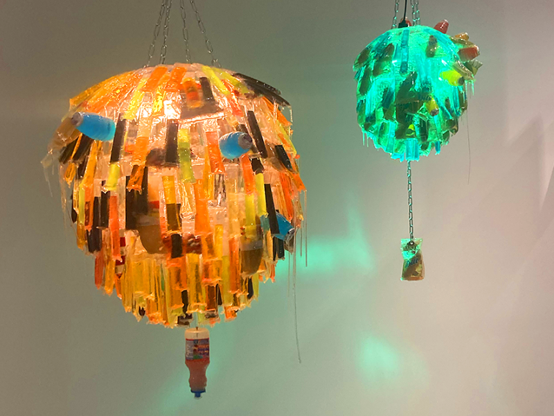 NowandLater I and II (2024), acrylic, pork rinds, icee pop, pickle, hot fries, hugs, epoxy, chain, motor, 36x30x30 inches