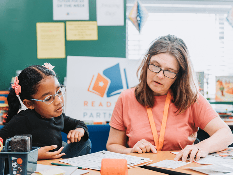 A Reading Partners volunteer tutor, right, working with a student.