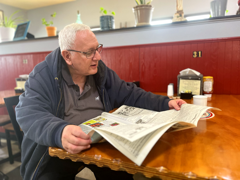 The Rev. John Cox, priest at St. Ann’s Church in Waubun, reading the Mahnomen Pioneer at Pappy’s Cafe: “(The Pioneer is) absolutely important.”