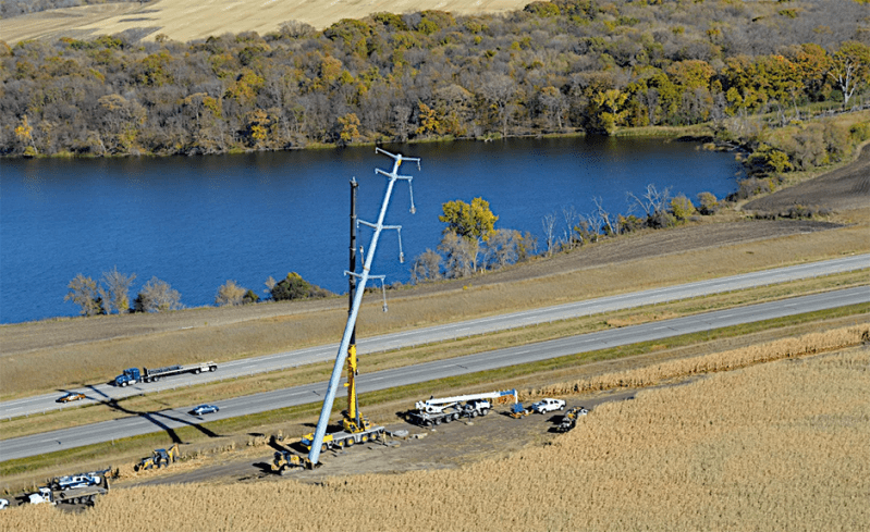 Workers set a transmission tower for the Capx 2020 line along a Minnesota highway.
