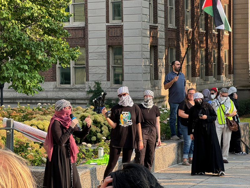 Pro-Palestine protesters hold up a single bullhorn during a Thursday protest outside of Morrill Hall calling for the University of Minnesota to divest from Israel.